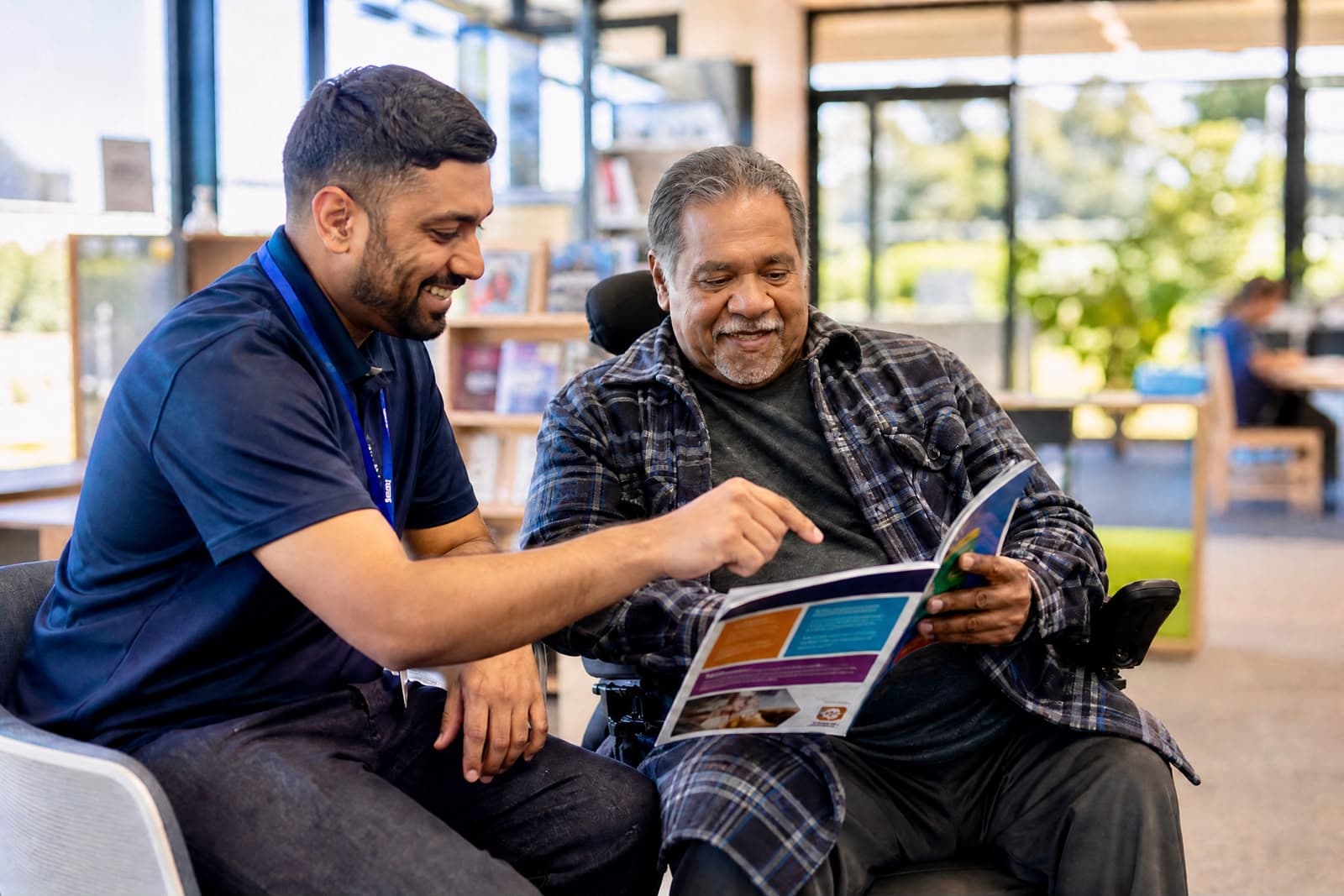 Support worker looking through information with a man using a wheelchair